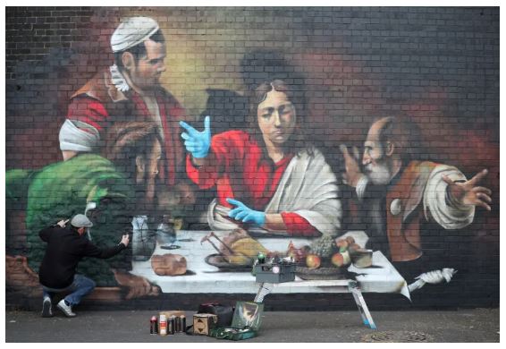A mural copying Caravggio's 'Christ in Emmaus' painting, but showing Jesus wearing blue latex gloves, a mark of coronavirus.