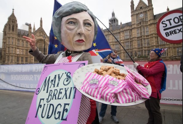 Lifesize figure of Theresa May with large label saying 'May's Brexit Fudge', holding out a plate of her fudge pieces. 