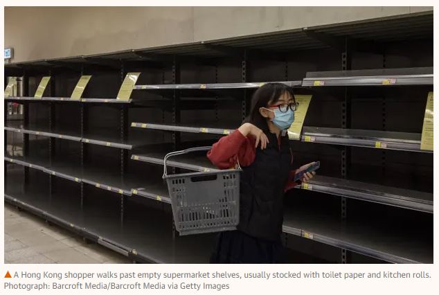 A Hong Kong shopper with hygiene mask on walks past empty shelves, normally stocked with toilet paper and kitchen rolls. The impact of the coronavirus epidemic.