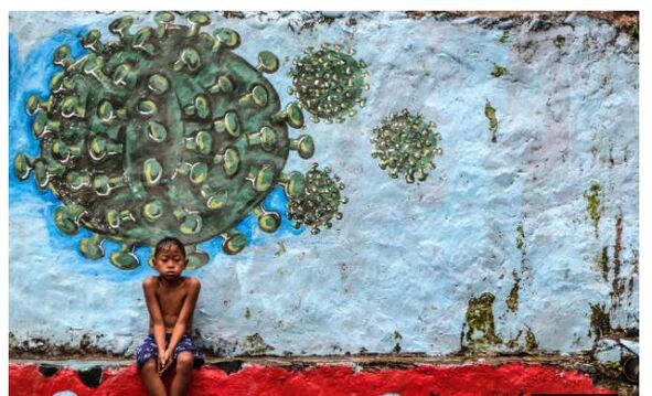 A mural from Bogor, West Java, showing a boy sitting in front of a green coronavirus, with its typical spherical shape with spikes sticking out all over it.