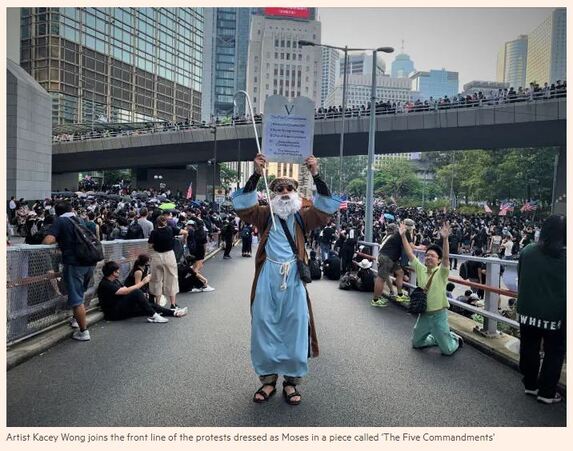 Performance artist Kacey Wong as Moses, holding up the Five Commandments, the five demands of the protesters.